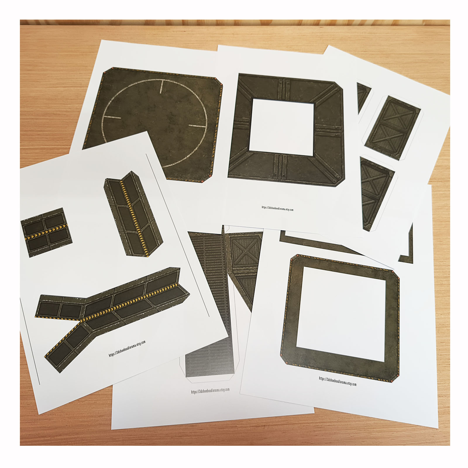 Printed Army Green helipad PDF pages on a brown wooden desk ready for the DIY papercraft build