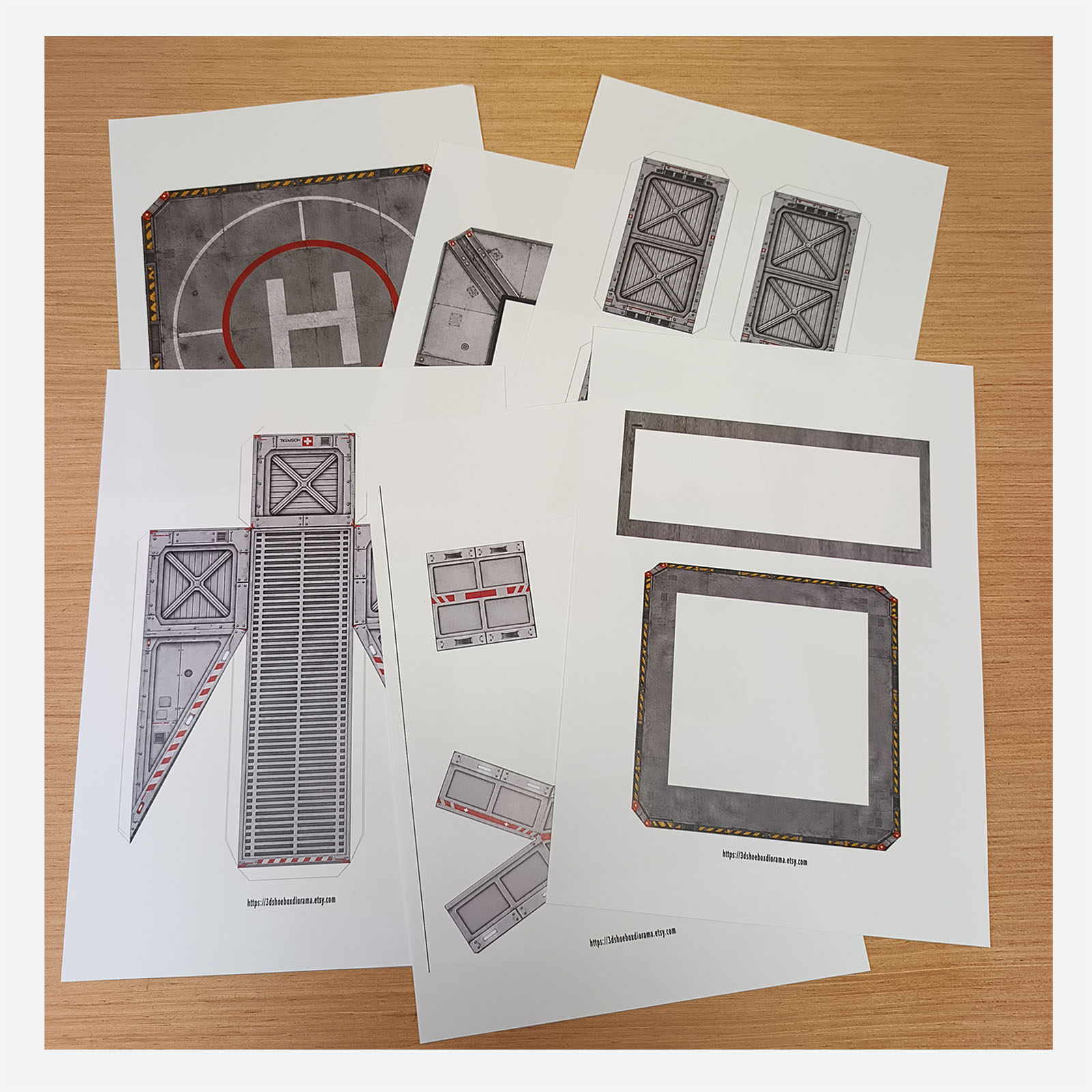 Printed hospital helipad PDF template on a wooden desk, ready to start the DIY papercraft build